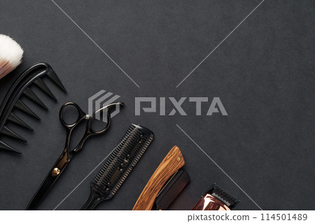 An Assortment of Professional Hairdressing Tools Laid Out on a Dark Surface 114501489