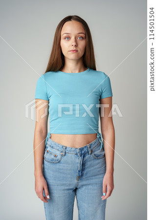 Young woman in blue t-shirt looking at camera with serious expression Young woman in blue t-shirt looking at camera with serious expression 114501504