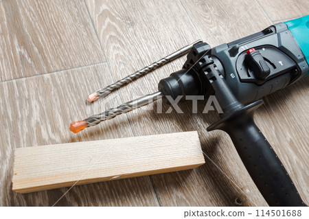 Electric hammer drill lies on a wooden table 114501688
