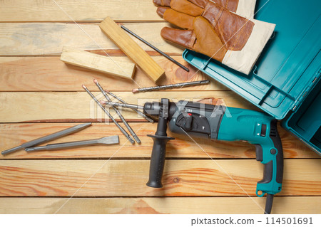 Electric hammer drill lies on a wooden table 114501691