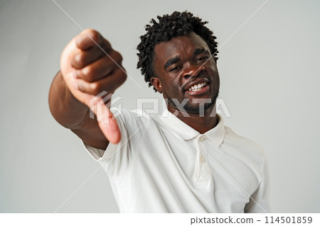 Young African Man Giving Thumbs Down Gesture Against a Neutral Background. Young African Man Giving Thumbs Down Gesture Against a Neutral Background. 114501859