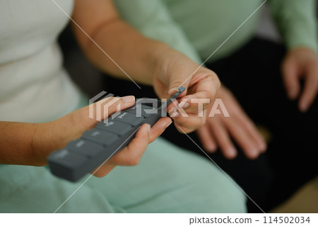 Closeup mature woman taking medicine from pill organizer box. Health care, medicine and treatment concept 114502034