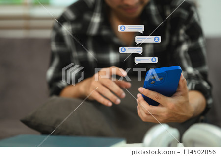 Smiling young man reading text message or notification on his smartphone 114502056