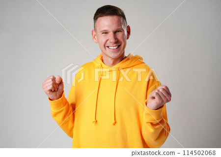 Portrait of a satisfied young man celebrating success over gray background Portrait of a satisfied young man celebrating success over gray background 114502068