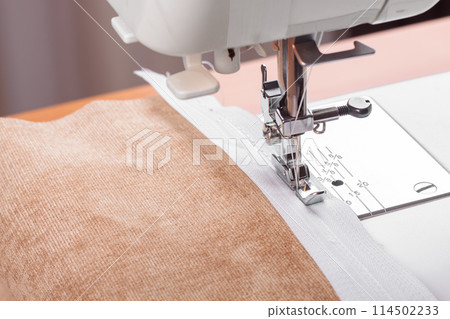 Modern sewing machine special presser foot with beige fabric and zipper, closeup Modern sewing machine special presser foot with beige fabric and zipper, closeup 114502233