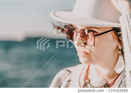 Portrait of a curly haired woman in a white hat and glasses on t 114502686