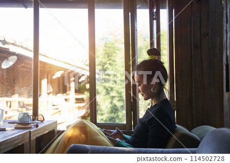 asian woman using mobile phone in coffee shop asian woman using mobile phone in coffee shop 114502728