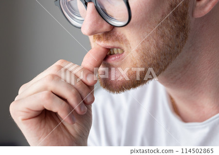 A man in glasses biting his fingernails. Unhygienic habits. A man in glasses biting his fingernails. Unhygienic habits. 114502865