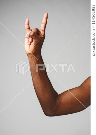 Hand Making the Rock N Roll Sign Against a Plain Gray Background 114502982