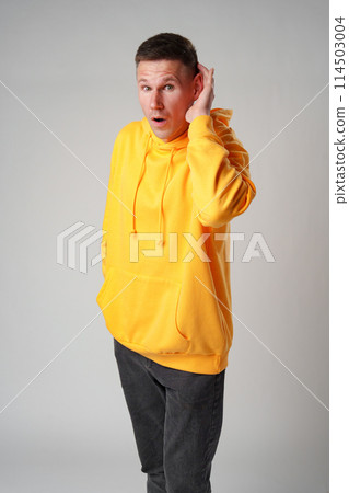 Portrait of young casual man with hand on ear who overhears on gray background Portrait of young casual man with hand on ear who overhears on gray background 114503004