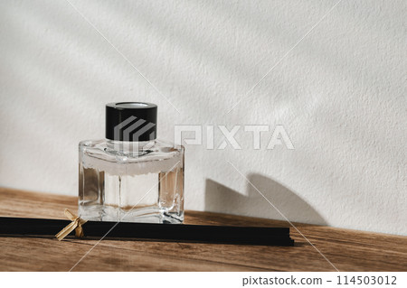 Elegant Perfume Bottle Bathed in Sunlight on a Wooden Surface 114503012