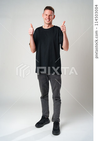 Portrait of a cheerful young man showing okay gesture on gray background 114503084