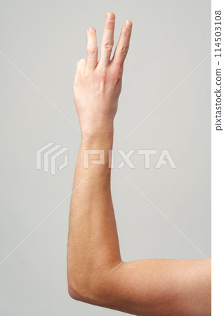 Male hand showing three fingers on gray background 114503108