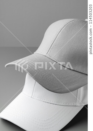 Two White Baseball Caps on a White Background 114503203