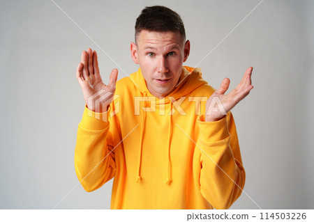 Portrait of surprised young man with shocked facial expression against gray background 114503226