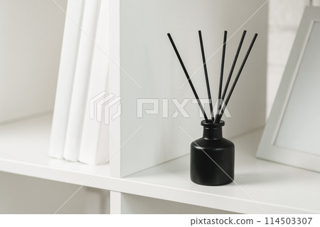 Elegant Black Reed Diffuser on White Shelf in Minimalist Home Decor Setting Elegant Black Reed Diffuser on White Shelf in Minimalist Home Decor Setting 114503307