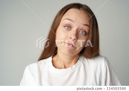 Clueless young worried woman dont know what to say, has no answer on gray background 114503500