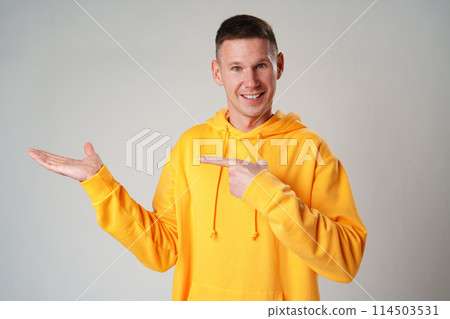 Young man pointing to the side to present a product on gray background Young man pointing to the side to present a product on gray background 114503531