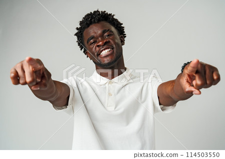 Young African Man Pointing at Something Against Gray Background Young African Man Pointing at Something Against Gray Background 114503550