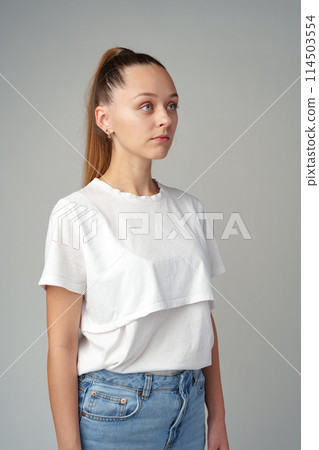 Portrait of a young woman in white T-shirt on gray background Portrait of a young woman in white T-shirt on gray background 114503554