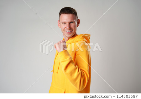 Portrait of a satisfied young man celebrating success over gray background 114503587