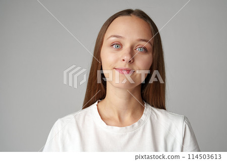 Portrait of a young woman in white T-shirt on gray background Portrait of a young woman in white T-shirt on gray background 114503613