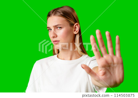 Young Woman Making Stop Sign Gesture on green background 114503875
