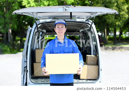 A male delivery driver carrying luggage outdoors 114504453