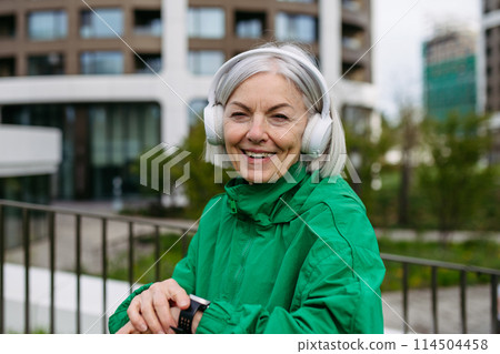 Mature woman checking her performance on smartwatche after run. Exercising after work for good mental health, physical health, relieving stress and boost mood. Mature woman checking her performance on smartwatche after run. Exercising after work for good mental health, physical health, relieving stress and boost mood. 114504458