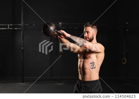 Man performing kettlebell swings, holding kettlebell in both hands. Routine workout for physical and mental health. Man performing kettlebell swings, holding kettlebell in both hands. Routine workout for physical and mental health. 114504623
