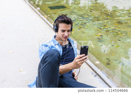 Man listening to music by a pond. 114504666