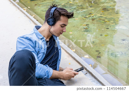 Man listening to music by a pond. 114504667