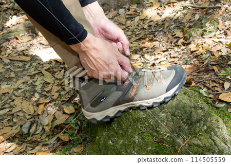 A man's hands tying the laces of his hiking boots A man's hands tying the laces of his hiking boots 114505559