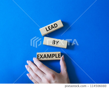 Lead by Example symbol. Concept word Lead by Example on wooden cubes. Businessman hand. Beautiful blue background. Business and Lead by Example concept. Copy space. Lead by Example symbol. Concept word Lead by Example on wooden cubes. Businessman hand. Beautiful blue background. Business and Lead by Example concept. Copy space. 114506080