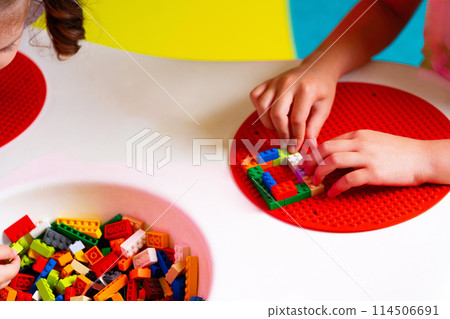 Child Engaged in Creative Play With Colorful Building Blocks on a Round Base 114506691