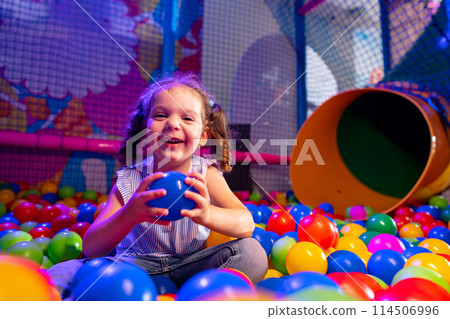 Joyful Young Girl Playing in a Colorful Ball Pit at an Indoor Playground Joyful Young Girl Playing in a Colorful Ball Pit at an Indoor Playground 114506996