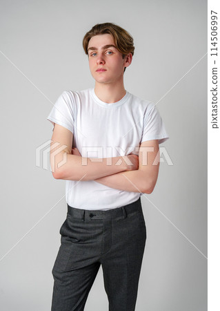Young Man With Arms Crossed Standing Against a Plain Background in a Studio Young Man With Arms Crossed Standing Against a Plain Background in a Studio 114506997