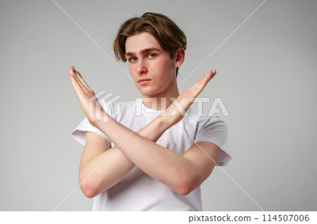 Young Man Making an X Sign With His Arms Against a Gray Background Young Man Making an X Sign With His Arms Against a Gray Background 114507006