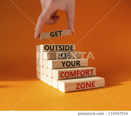 Get outside of your comfort zone symbol. Concept words Get outside of your comfort zone on wooden blocks. Businessman hand. Beautiful orange background. Business concept. Copy space. 114507054