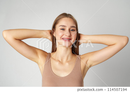 Smiling young woman posing to camera over gray background in studio Smiling young woman posing to camera over gray background in studio 114507194
