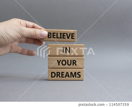 Believe in your Dreams symbol. Concept words Believe in your Dreams on wooden blocks. Businessman hand. Beautiful grey background. Business and Believe in your Dreams concept. Copy space 114507359