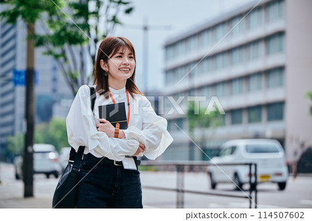 一位年輕女子胸前背著筆記本行走 一位年輕女子胸前背著筆記本行走 114507602