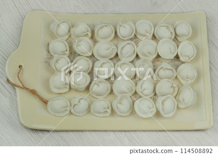 Dumplings with beef on the kitchen board. Raw dumplings with meat. Home cooking. Dumplings with beef on the kitchen board. Raw dumplings with meat. Home cooking. 114508892