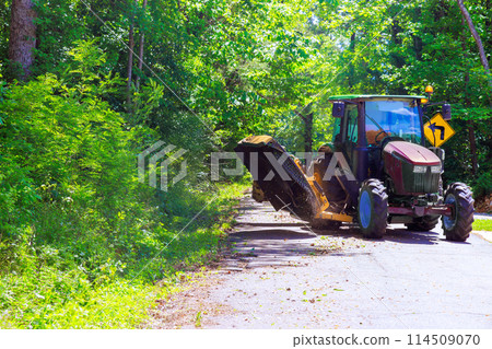 Cutting grass branches on both sides of road with municipal service tractor mower 114509070