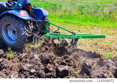 During spring, tractor ploughs field, cultivates soil, prepares it for sowing grain 114509072