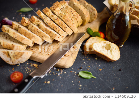 sliced bread on wooden cutting board on dark table 114509120