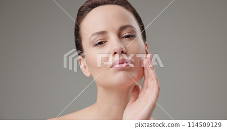 Beauty, health, cosmetics, anti-aging therapy and skin care concept - young beautiful brunette Caucasian woman touching face and looking at camera 114509129