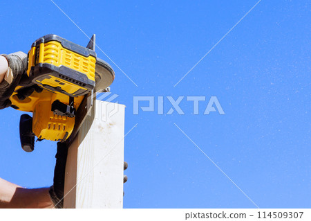 Carpenter cutting wooden beam with handsaw during woodworking 114509307