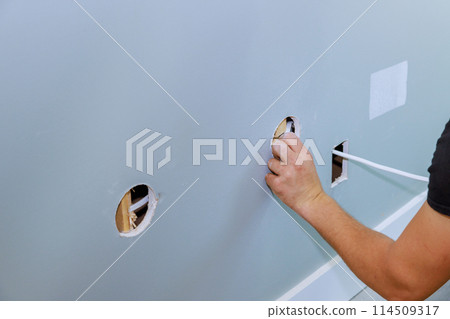 Electrician installing new current wires on an interior wall during apartment renovation 114509317