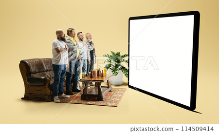 Men standing by couch at home, looking n 3d model of screen, and singing football anthem before game start 114509414